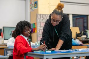 Young girl getting help with homework by a teacher